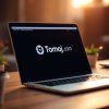 A photograph of Tomoj.com Software interface on a laptop screen, illuminated by soft warm ligh...jpg